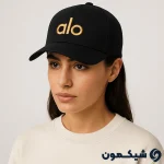 مدل زن با کلاه بیسبالی Alo مشکی با لوگوی طلایی، نمای نیم‌رخ