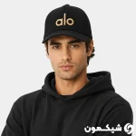 مدل مرد با کلاه بیسبالی Alo مشکی با لوگوی طلایی، استایل اسپرت هودی