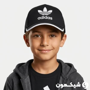 پسربچه‌ای با سوییشرت ذغالی و کلاه بچگانه adidas پشت تور لبه سفید در نمای روبرو